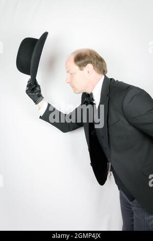 Profil des eleganten britischen Butlers, der sich in einladender Weise verbeugt und den Bower Hut abgibt. Konzept der Dienstleistungsbranche und der professionellen Gastfreundschaft. Stockfoto