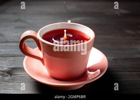 Tasse Tee mit einem Tropfen Milch auf Holzboden Stockfoto