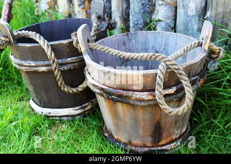 Eine Nahaufnahme von zwei altmodischen hölzernen Wassereimern mit Seilgriffen. Stockfoto