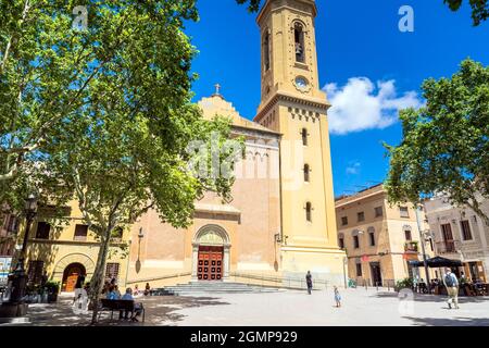 Barcelona, Spanien - 7. Juli 2017: Tagesansicht von Plaça de la Concòrdia und Església de Santa Maria del Remei mit Einheimischen auf Bänken in Barcelona, Spanien. Stockfoto