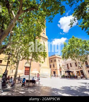 Barcelona, Spanien - 7. Juli 2017: Tagesansicht von Plaça de la Concòrdia und Església de Santa Maria del Remei mit Einheimischen auf Bänken in Barcelona, Spanien. Stockfoto