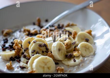 Gesunder Haferbrei mit Banane, Walnüssen und Kakaonibs. Stockfoto