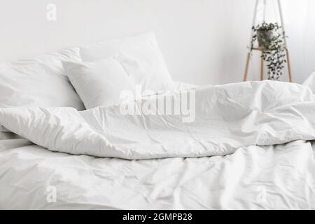 Weiches, ungetautes Bett, bequemes Kissen, weiße Bettwäsche ohne jemanden Stockfoto