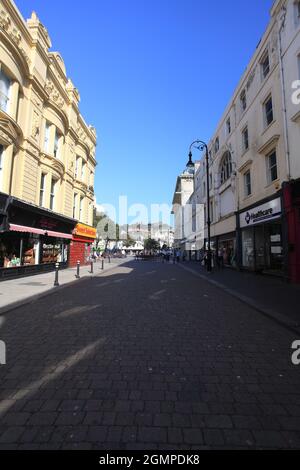 Robertson Street in Hastings (America Ground) mit seinen Geschäften und Cafés und Blick auf das normannische Schloss, Hastings, East Sussex, Großbritannien Stockfoto