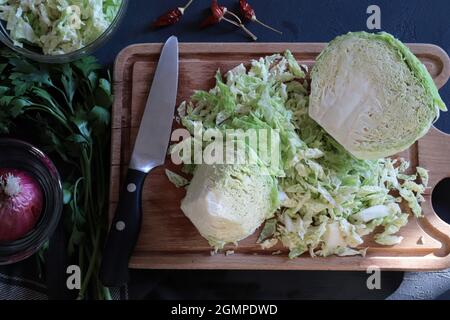 Den Kohl auf dem Holzschneidebrett schneiden. Direkt darüber. Stockfoto