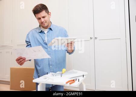 Frustriert Und Verwirrt Mann Leseanweisungen Und Zusammen Selbstmontage Möbel Zu Hause Stockfoto