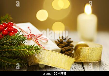 Weihnachtskomposition mit Geschenkbox Tannenzweig aus Kiefernholz und brennender Kerze Stockfoto