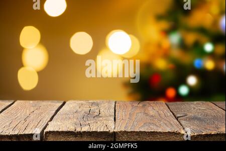 Weihnachtlicher leerer Holztisch über dem weihnachtsbaum und verschwommenes leichtes Bokeh Stockfoto