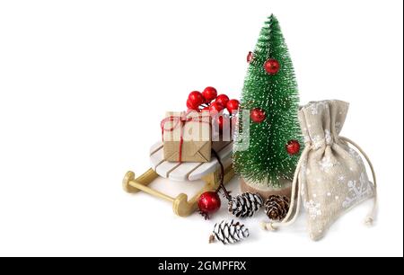 Miniatur-Weihnachtsbaum mit Weihnachtsgeschenken auf dem Schlitten isoliert auf Weiß. Stockfoto
