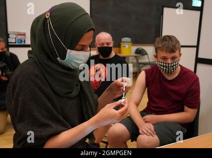 Die Apothekerin Anila Akram bereitet sich darauf vor, Jamie Stuart von der Cathkin High School im Fernhill Community Center in Rutherglen, South Lanarkshire, einen Impfstoff zu verabreichen. Bilddatum: Montag, 20. September 2021. Stockfoto