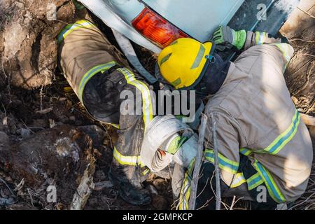 Feuerwehrleute retten ein gefallenes Auto im Graben. Stockfoto