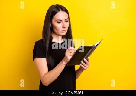 Portrait von charmanten Dame aussehen interessiert Arme halten Notizbuch nehmen Notizen isoliert auf gelbem Hintergrund Stockfoto