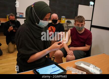 Die Apothekerin Anila Akram bereitet sich darauf vor, Jamie Stuart von der Cathkin High School im Fernhill Community Center in Rutherglen, South Lanarkshire, einen Impfstoff zu verabreichen. Bilddatum: Montag, 20. September 2021. Stockfoto