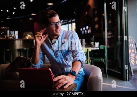 kaukasischer, hübscher Mann mit Brillen, der an der Bar mit Ditigaltablette arbeitet Stockfoto