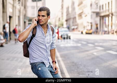 Junger, hübscher Tourist, der sein Smartphone in der Via Laietana - Barcelona benutzt Stockfoto