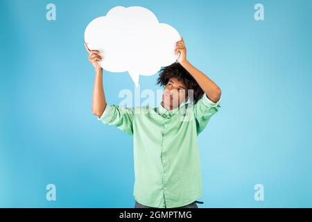 Denkkonzept. Nachdenklicher afroamerikanischer Kerl, der Sprechblase hält und anschaut, grübelnd, blauer Hintergrund Stockfoto