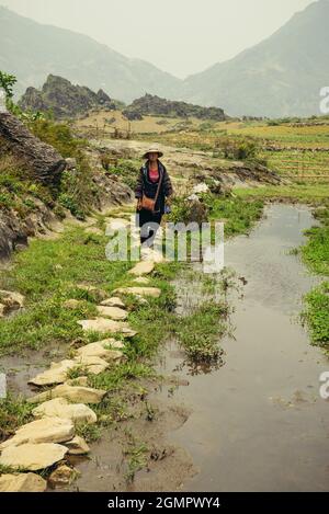 Sapa, Vietnam - 15. April 2016: Frau (Black Hmong), die in nationaler Kleidung durch die Hügel Südostasiens wandert. nordvietnamesische Berge in Stockfoto