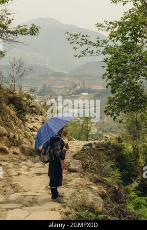 Sapa, Vietnam - 15. April 2016: Frau (Black Hmong), die in nationaler Kleidung durch die Hügel Südostasiens wandert. nordvietnamesische Berge in Stockfoto