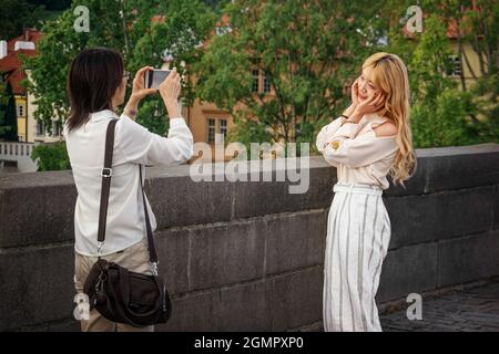 13. August 2017 Prag, Tschechische Republik. Asiatische Touristen werden vor dem Hintergrund der Sehenswürdigkeiten der Stadt fotografiert. Paare nehmen Selfies dagegen Stockfoto