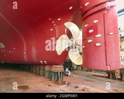 Reparatur und Restaurierung von Schiffen auf der Werft. Achtern eines großen Frachtschiffes mit Lenkung und Propeller. Trockenfrachtschiff wird im Trockendock repariert Stockfoto