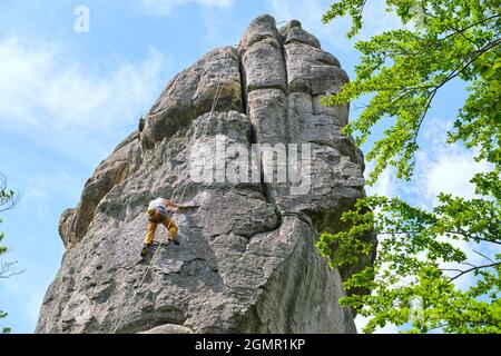 Entschlossener Kletterer, der die steile Wand des felsigen Berges hochklettert. Sportler überwinden schwierige Route. Engagement in Extremsport und Klettern Hobb Stockfoto