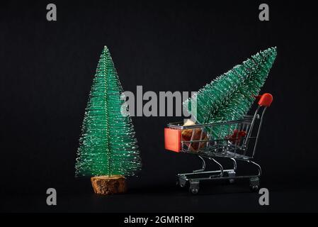 Frohe Weihnachten und ein glückliches neues Jahr Komposition. Kleiner Spielzeug-weihnachtsbaum im Warenkorb auf dunklem Hintergrund. Schöner Grußwagen und Banner. 2022 Neujahrskonzept Stockfoto
