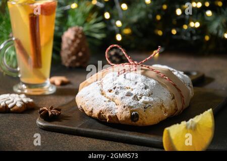 Traditionelles, mit Stollen dekoriertes rotes Festseil, immergrüne Äste und Girlande auf einem braunen Festtisch. Weihnachtsfeiertage traditionelle Leckereien. Schließen Sie U Stockfoto