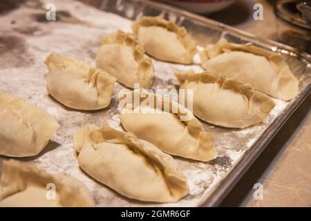 Hausgemachte asiatische Knödel sitzen auf einem Tablett und warten darauf, gekocht zu werden Stockfoto