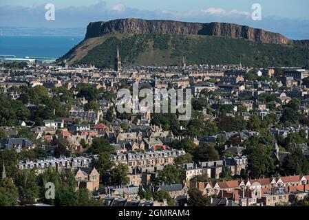 Wohnhäuser in Süd-Edinburgh mit Salisbury Crags im Hintergrund, aufgenommen aus Blackford Hill, Edinburgh, Schottland, Großbritannien. Stockfoto