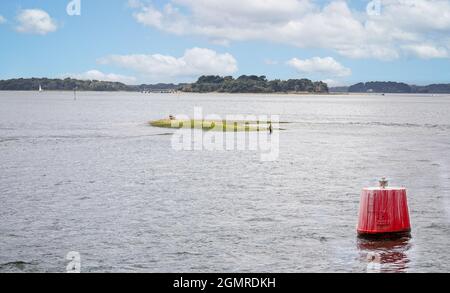 Einsamer Fischer, der am 19. September 2021 in Poole Harbour, Poole, Dorset, Großbritannien, in der Nähe der roten Marktboje ein isoliertes Land fischt Stockfoto