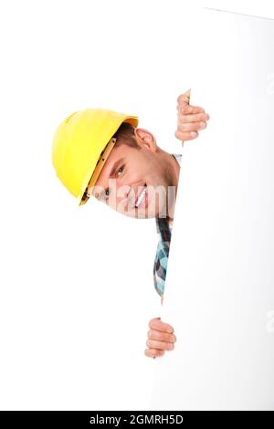 Junger glücklicher Ingenieur in einem Helm, der sich hinter einem leeren Poster versteckt Stockfoto