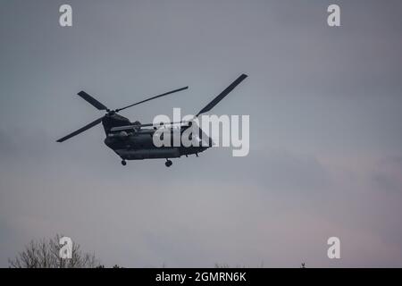 RAF Chinook Tandem-Rotor CH-47 Hubschrauber fliegt schnell und tief in einem wolkigen blauen grauen Himmel auf einer militärischen Kampfübung, Wilts UK Stockfoto