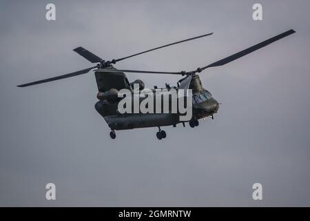 RAF Chinook Tandem-Rotor CH-47 Hubschrauber fliegt schnell und tief in einem wolkigen blauen grauen Himmel auf einer militärischen Kampfübung, Wilts UK Stockfoto