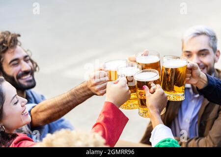 Eine Gruppe von multirassischen, fröhlichen Freunden, die mit Bieren in der Terrassenbrauerei-Bar jubeln Stockfoto