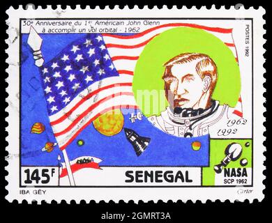 MOSKAU, RUSSLAND - 6. NOVEMBER 2019: Die im Senegal gedruckte Briefmarke zeigt John Glenn und die Flagge der USA, 30. Jahrestag des ersten bemannten US-Amerikaners Stockfoto