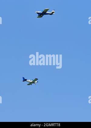 Zwei Leichtflugzeuge fliegen während einer Flugschau gegen einen klaren blauen Himmel auseinander. Stockfoto