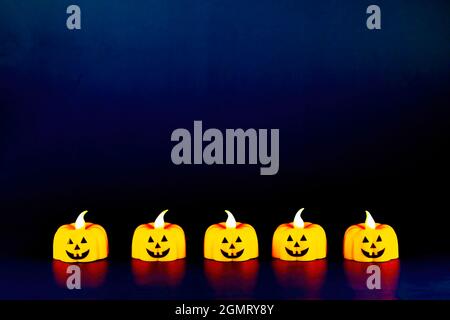 Fünf helle Kürbiskerzenlichter auf dunklem Hintergrund. Halloween-Konzept Stockfoto
