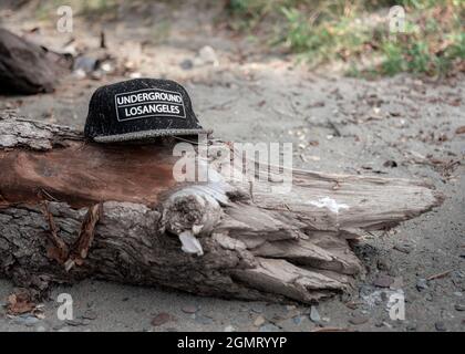 06. August 2020 , Altay Republik, Russland: Verlorene Baseballmütze an einem Strand mit Bergsee Sand und Müll mit Notiz in englischer UNDERGROUND LO Stockfoto
