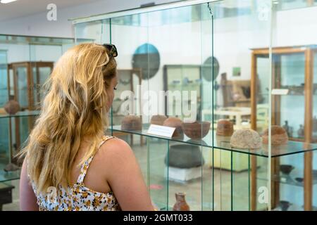 Hinter dem Fenster ist ein Museum mit Reliquien, Skulpturen und Töpferwaren aus den alten Zivilisationen Kappadokiens ausgestellt. Eine schöne junge Frau Stockfoto