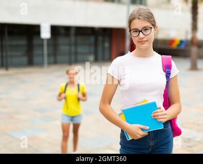 Mädchen mit Copybooks, die neben dem Schulgebäude stehen Stockfoto