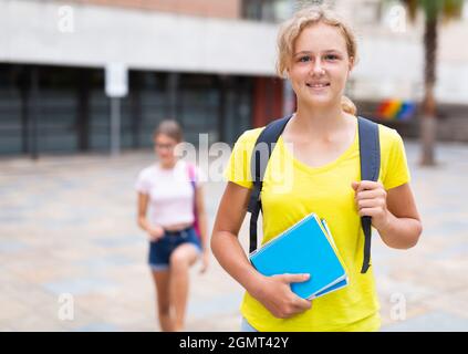 Mädchen mit Copybooks, die neben dem Schulgebäude stehen Stockfoto