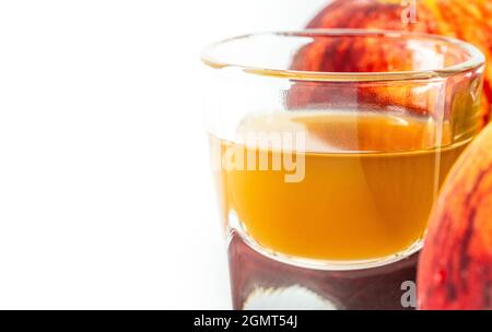 Nahaufnahme Bio Apfelessig mit der Mutter in einer kleinen Glasaufnahme stehen zwei rote Äpfel neben dem Glas, Bild auf weißem Hintergrund. Leeres Spa Stockfoto