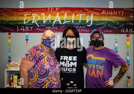 Foto des Führungsteams des Merced Pride Center Cristina Vara (lft), Jennifer McQueen (cntr) und Eli Sachse (rt) unter einem Regenbogengleichheitszeichen. Stockfoto