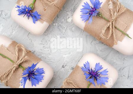 Handgemachte Naturseife mit Bastelpapier, Geißel und blauen Blumen verziert. Bio-Kosmetik-Konzept. Draufsicht Flat Lay Copy Space Vorlage für d Stockfoto