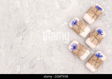 Handgemachte Naturseife mit Bastelpapier, Geißel und blauen Blumen verziert. Bio-Kosmetik-Konzept. Draufsicht Flat Lay Copy Space Vorlage für d Stockfoto