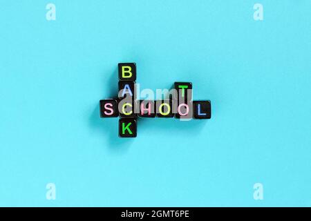 Back to School Text aus bunten Buchstaben auf schwarzen Würfeln in Form von Kreuzworträtsel, blauer Hintergrund. Konzeptbildung und Beginn von sch Stockfoto