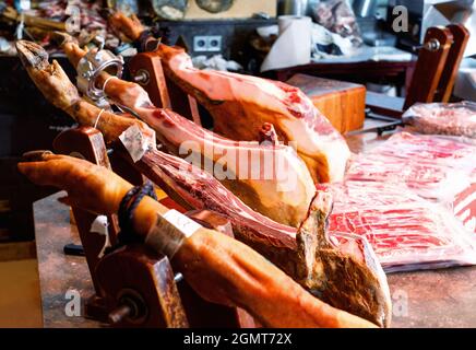 Die Beine des traditionellen spanischen Jamons sind auf hölzernen Jamoneras befestigt und stehen zum Verkauf bereit Stockfoto