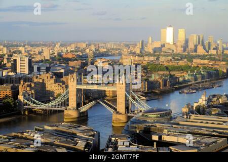 Erhöhter Blick flussabwärts entlang der Themse zur Isle of Dogs mit offener Tower Bridge kurz vor Sonnenuntergang in London, England Stockfoto