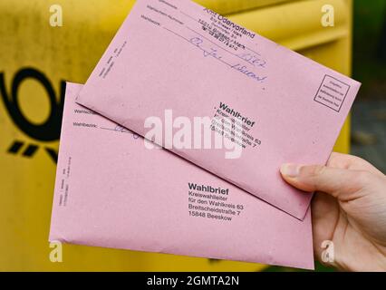 Sieversdorf, Deutschland. September 2021. Eine Person zeigt zwei Abwesenheitsstimmzettel vor einem Briefkasten der Deutschen Post. In den Umschlägen befinden sich die aktuellen Stimmzettel sowie die Wahlunterlagen als Briefwahl zur Bundestagswahl am Sonntag, 26. September 2021. Quelle: Patrick Pleul/dpa-Zentralbild/ZB/dpa/Alamy Live News Stockfoto