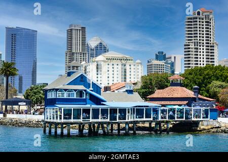 Das San Diego Pier Restaurant im blau-weißen Retro-Stil auf Stelzen im Seaport Village mit sich abzeichnenden Hochhäusern an der Bucht von San Diego, CA Stockfoto